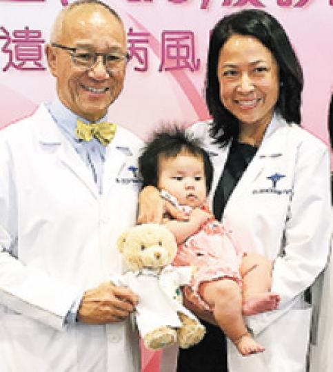 養和醫院副院長暨婦女健康及產科部主管陳煥堂（左）、生殖醫學專科醫生駱紅（右），與本港首個採用NGS作PGS出生的嬰兒合照。（鄧可盈攝）