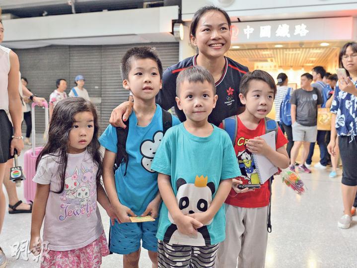 到紅磡站迎接李慧詩返港的市民中，包括7歲的John（前左二起）、5歲「壽星」Issac及6歲的Asher，均是「牛下女車神」的小粉絲，他們昨日送上自己繪畫的畫作給李慧詩後，興奮與她合照。（鄧宗弘攝）