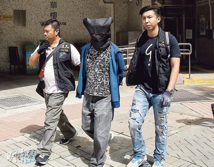 警方拘捕一名涉及旺角衝突被捕的男子，並到其寓所搜查，將他黑布蒙頭、鎖上手銬押返警署扣查。（林智傑攝）警方探員展示在行動中檢走的證物，包括電腦、口罩及手套等。（林智傑攝）