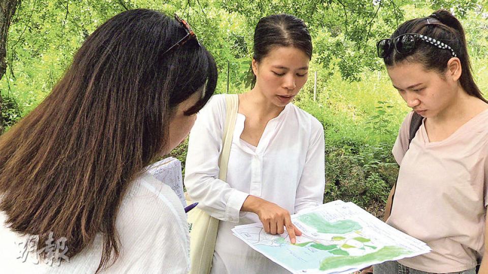 守護大嶼聯盟成員小燕（中）了解東涌谷的規劃文件後，發現有關規劃圖只強調如何發展，沒把會被犧牲的農地或綠化地方標示，所以她自製一張對照圖，希望能讓更多街坊了解東涌谷現有的資源有多珍貴。（楊凱力攝）