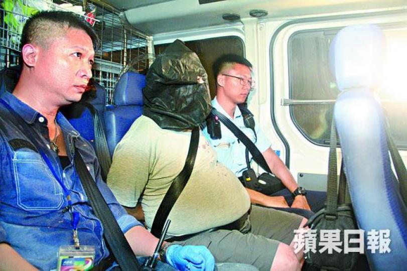 ■涉殺死同事的保安員被警員蒙頭帶署。 ■涉殺死同事的保安員被警員蒙頭帶署。