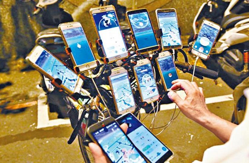 ■陳三元裝備11支手機瘋玩Pokémon GO。台灣《蘋果日報》■途人圍觀陳三元捉精露靈。台灣《蘋果日報》 ■陳三元裝備11支手機瘋玩Pokémon GO。台灣《蘋果日報》■途人圍觀陳三元捉精露靈。台灣《蘋果日報》