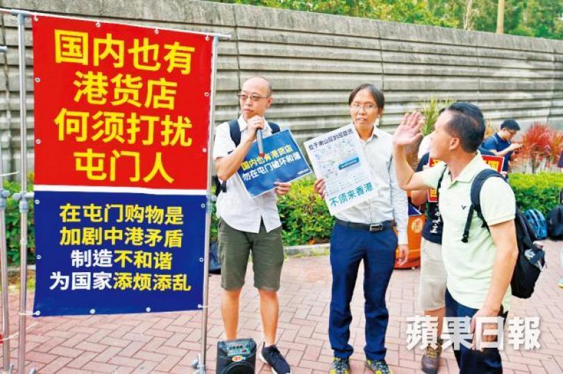 譚凱邦（中）等人在巴士站擺放簡體字標語，勸內地客留在內地消費。多名警員在場維持秩序，更「開路」協助內地客上巴士。黎樹雄攝
