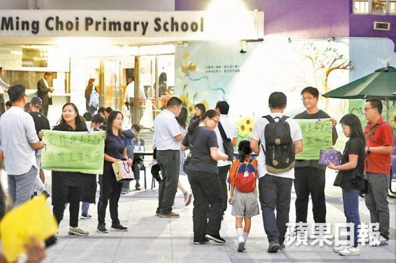 有教職員昨在校外呼籲家長繫上紫絲帶,以示支持校長和教師。 有教職員昨在校外呼籲家長繫上紫絲帶,以示支持校長和教師。