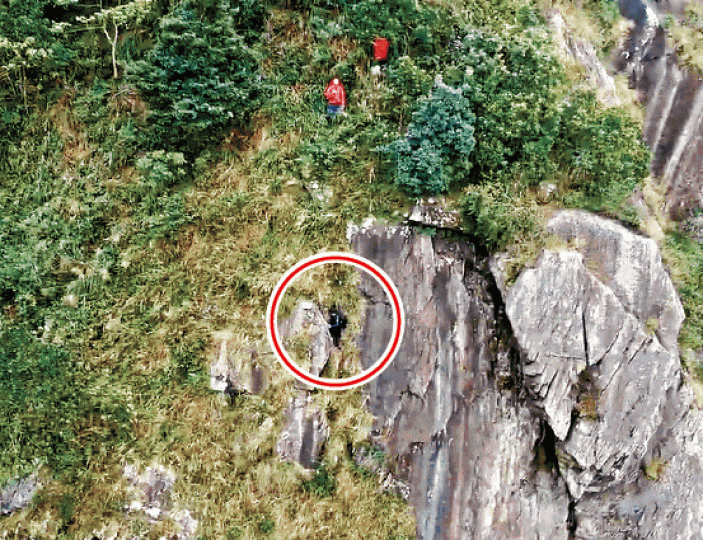 藍衣男(紅圈示)被困峭壁,民安隊登山拯救。航拍機搜救服務提供圖片救援人員繼續在飛鵝山搜索失蹤女子。劉永明攝 藍衣男(紅圈示)被困峭壁,民安隊登山拯救。航拍機搜救服務提供圖片救援人員繼續在飛鵝山搜索失蹤女子。劉永明攝