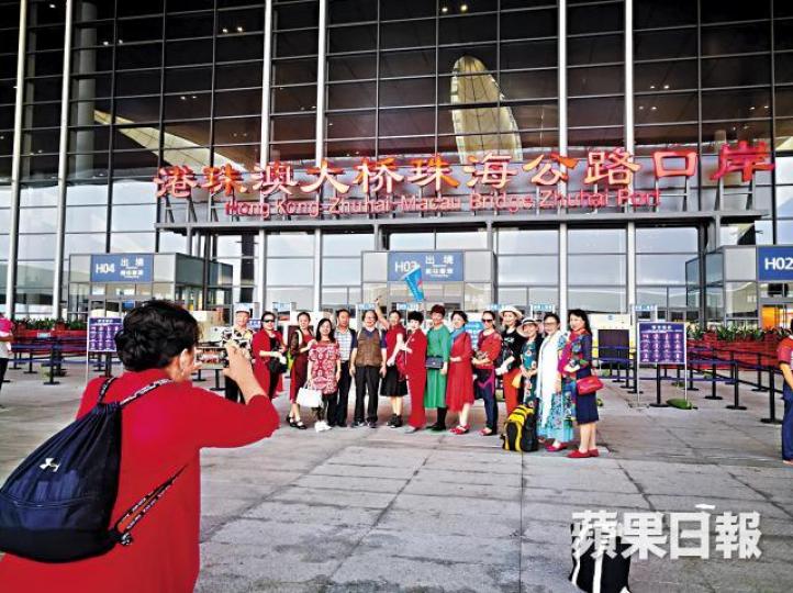 8:00am集合　衣着艷麗的旅客，在港珠澳大橋珠海口岸留影。林  熊攝8:36am出境　記者參加的鴨仔團從珠海出境後，搭金巴前往香港口岸。8:45am上橋　金巴駛經港珠澳大橋，團友在巴士上層「留倩影」。龔蕙芝攝10:08am抵港　記者一團人較早到達東涌，等候約10分鐘就能登上昂平纜車。11:30am昂坪　領隊指自己數日前已被傳媒拍攝指他「做黑工」，故不願上鏡。