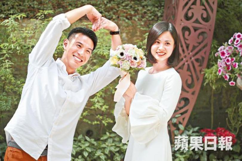 參加婚禮的情侶在佈景前拿着花球及擺出心形姿勢。何家達攝 參加婚禮的情侶在佈景前拿着花球及擺出心形姿勢。何家達攝