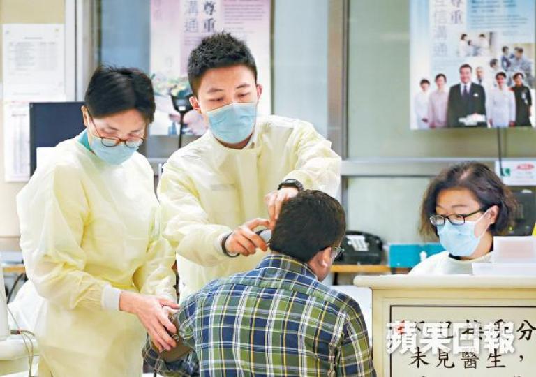 醫護人員戴口罩、穿保護衣為病人診治。 醫護人員戴口罩、穿保護衣為病人診治。