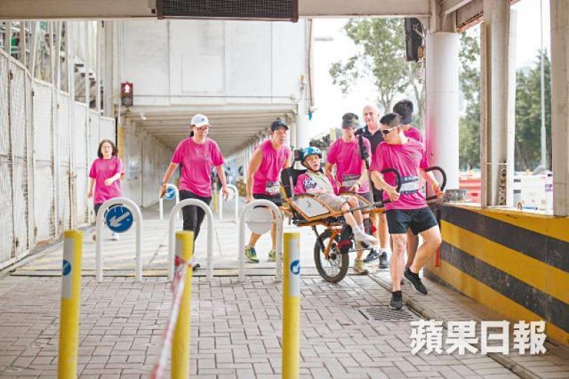 比賽只在行人路進行,義工前進時面對不少障礙。極地同行創辦人Steve將偉文抱上特製輪椅。義工們小心地把偉文的腳固定在輪椅上。偉文不能說話,但眼神堅定。跑手除了要顧及自己和隊友的步伐,更要保持輪椅平衡,一心多用。這枚獎牌除是完賽證明,更給予傷健人士無限鼓勵。 比賽只在行人路進行,義工前進時面對不少障礙。極地同行創辦人Steve將偉文抱上特製輪椅。義工們小心地把偉文的腳固定在輪椅上。偉文不能說話,但眼神堅定。跑手除了要顧及自己和隊友的步伐,更要保持輪椅平衡,一心多用。這枚獎牌除是完賽證明,更給予傷健人士無限鼓勵。