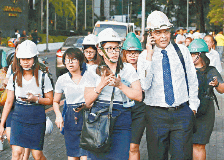 地震後馬尼拉大批辦公室職員戴頭盔走到街上。美聯社 地震後馬尼拉大批辦公室職員戴頭盔走到街上。美聯社