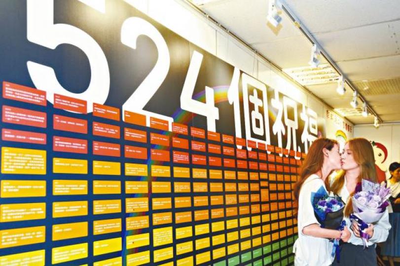 台北信義戶政事務所昨佈置「524個祝福」的看板祝賀同婚者。台灣蘋果新聞網簡至潔(右)為許秀雯戴上婚戒。何穎賢攝 台北信義戶政事務所昨佈置「524個祝福」的看板祝賀同婚者。台灣蘋果新聞網簡至潔(右)為許秀雯戴上婚戒。何穎賢攝