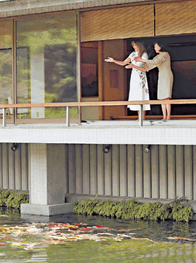 梅拉尼婭(左)向安倍妻子學習拍掌召喚鯉魚。路透社 梅拉尼婭(左)向安倍妻子學習拍掌召喚鯉魚。路透社